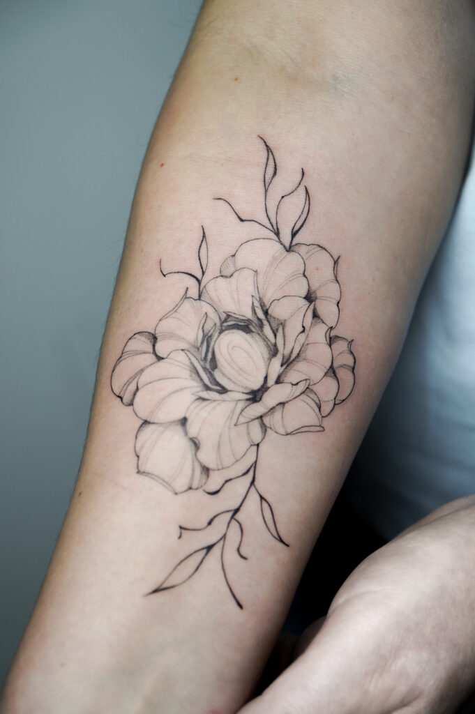 Subtelny lineworkowy tatuaż kwiatowy na przedramieniu w stylu szkicu, idealny dla fanów minimalizmu – wykonany w Fineline Tattoo Gallery.