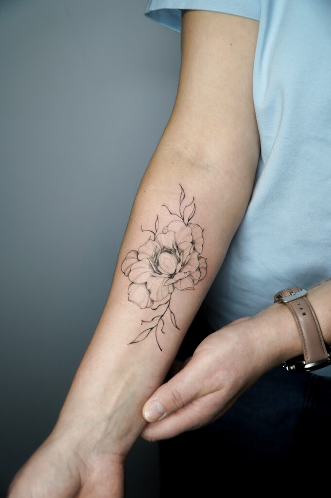Tatuaż z konturowanym kwiatem na przedramieniu – szkicowy styl z precyzyjnymi liniami, wykonany w Fineline Tattoo Gallery.