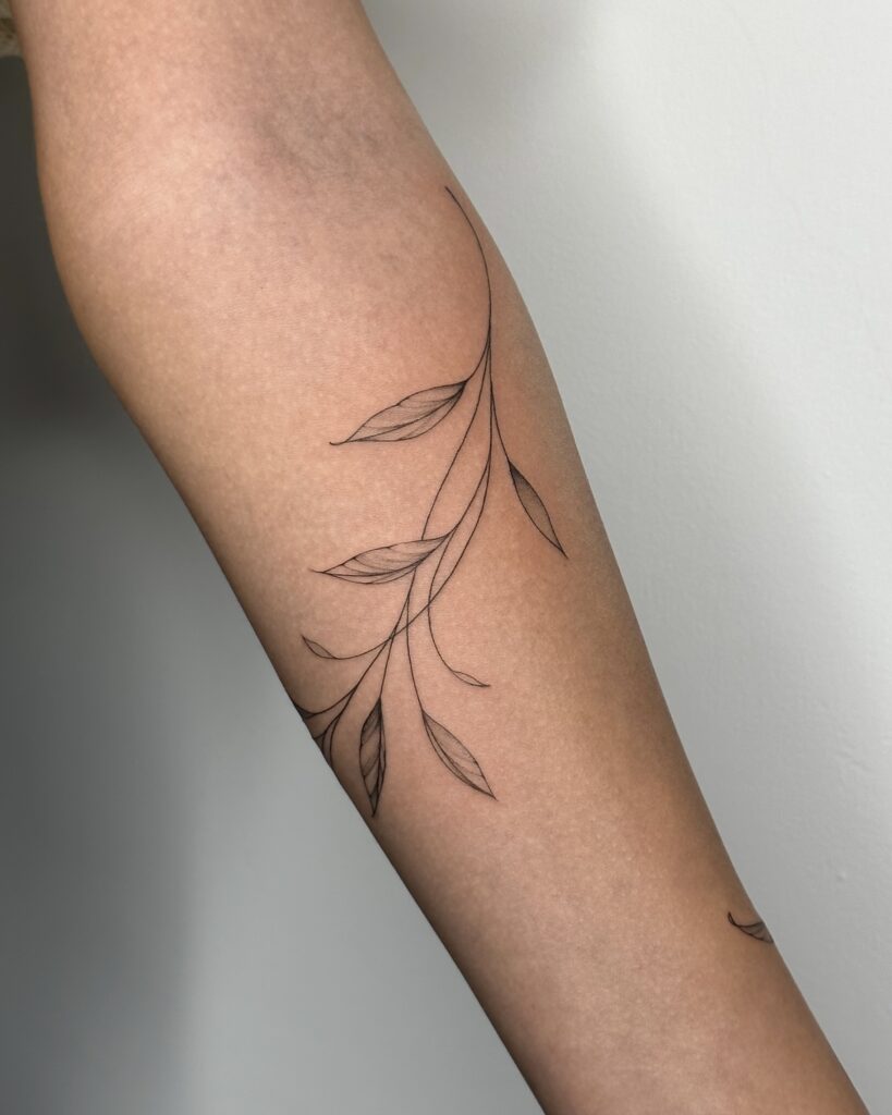Botanical fine line leaf tattoo in black ink placed on the forearm. A delicate and minimal nature-inspired design created at Fineline Tattoo Gallery in Krakow.