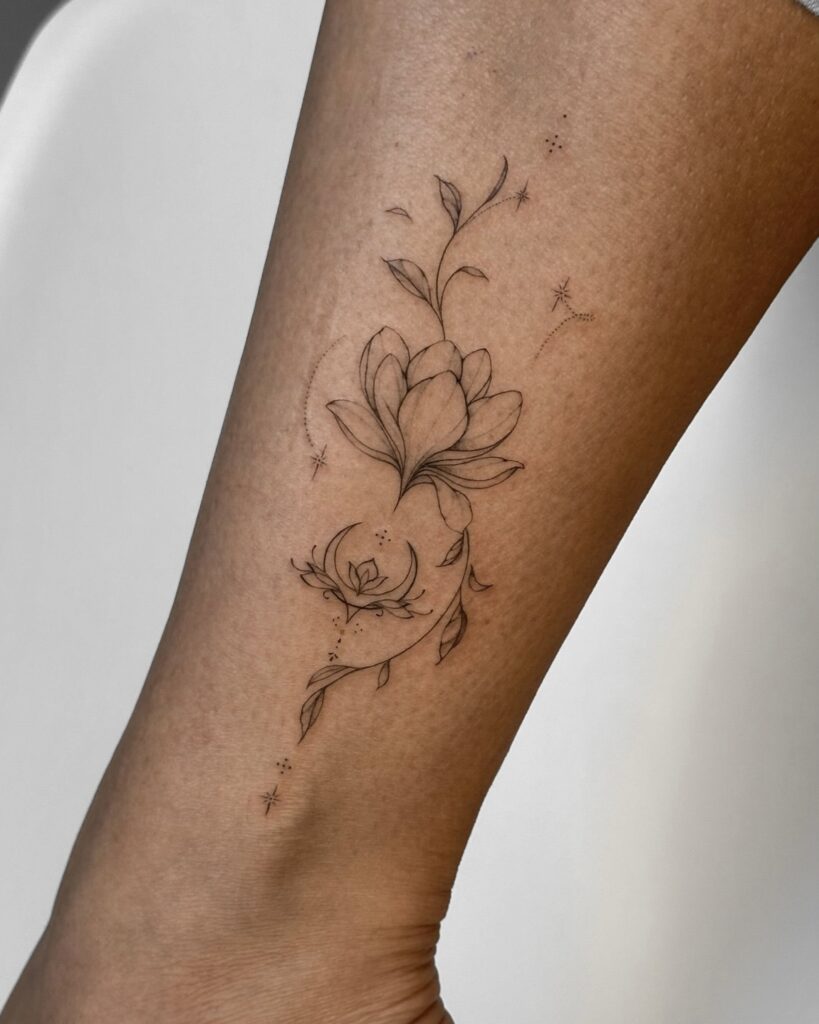 Elegant fine line floral tattoo in black ink placed on the ankle. A minimal and delicate botanical design created at Fineline Tattoo Gallery in Krakow.