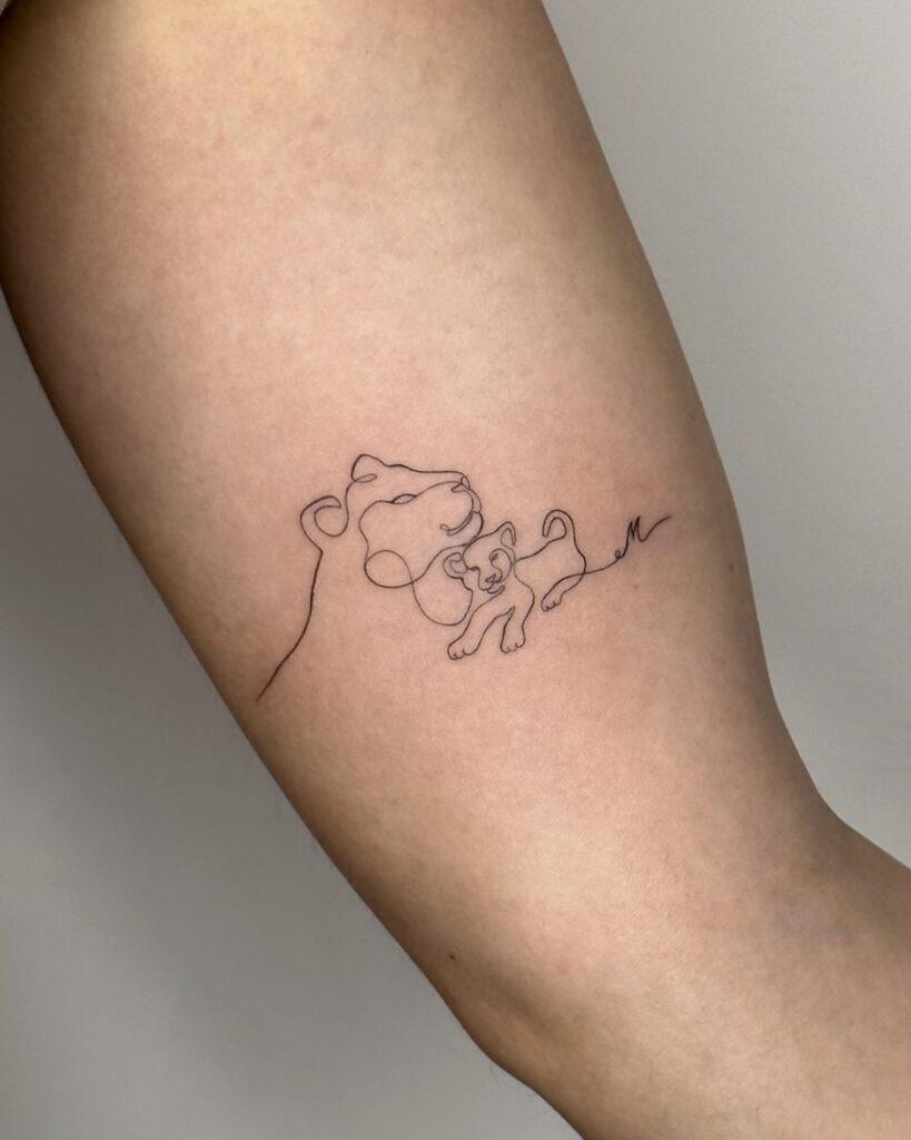 Fine line line-art tattoo of a lioness with her cub, placed on the arm. A delicate and meaningful black ink design symbolizing protection, love, and connection, created at Fineline Tattoo Gallery in Krakow.