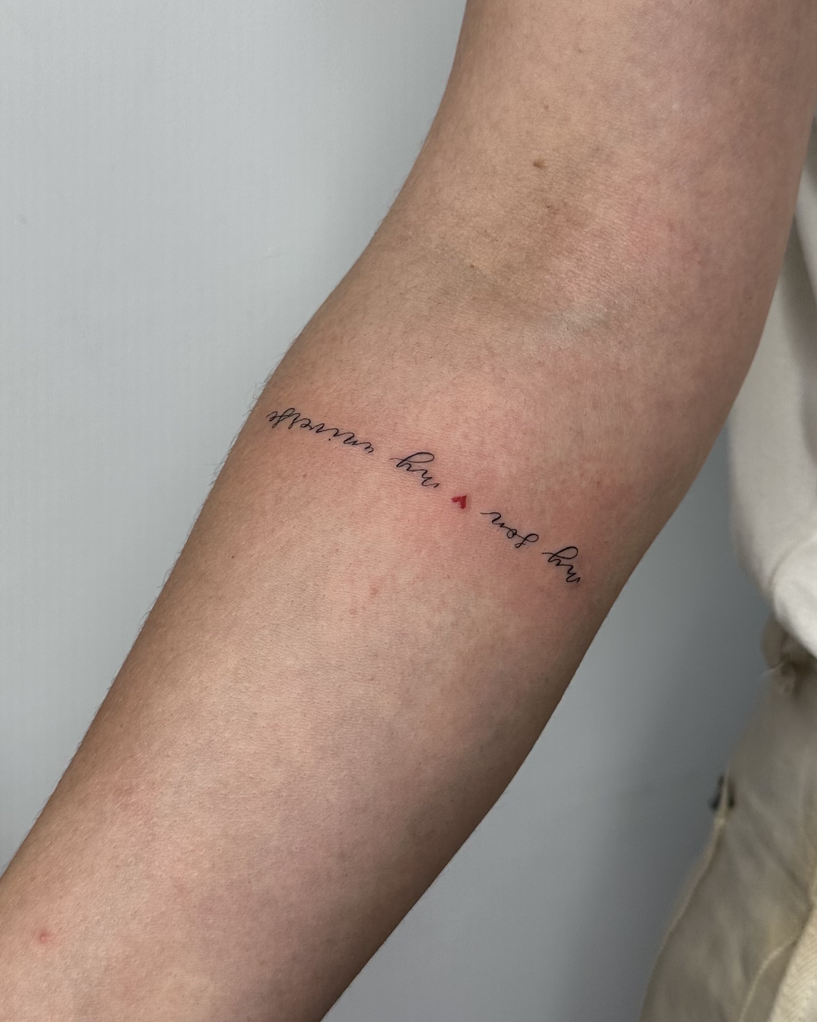 Delikatny tatuaż z napisem „my sun my moon” wykonany cienką linią z małym czerwonym serduszkiem. Subtelny, osobisty akcent na przedramieniu, idealny na codzienną biżuteryjną estetykę.