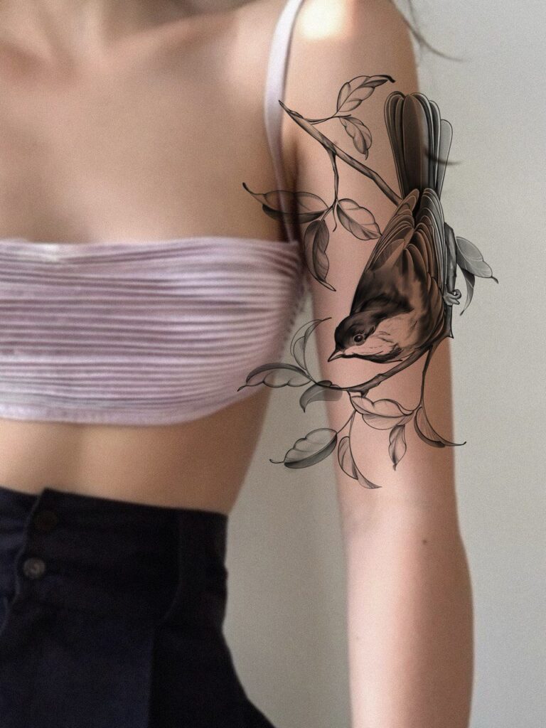 Fine line bird tattoo design featuring a delicate bird perched on a branch with soft leaves. An elegant, minimalist black and grey tattoo concept created with attention to lightness and natural flow. Tattoo design by Olga Sankova (olga_sankova_tattoo).