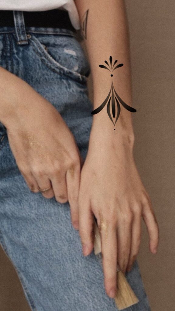 Minimalist ornamental tattoo design in blackwork style, placed on the forearm. A clean, symmetrical composition with fine line details, emphasizing elegance, balance, and subtle decorative elements. Tattoo design by Olga Sankova (olga_sankova_tattoo).